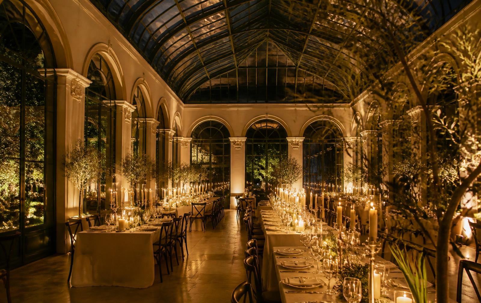 Candlelit tables set inside a glass orangery